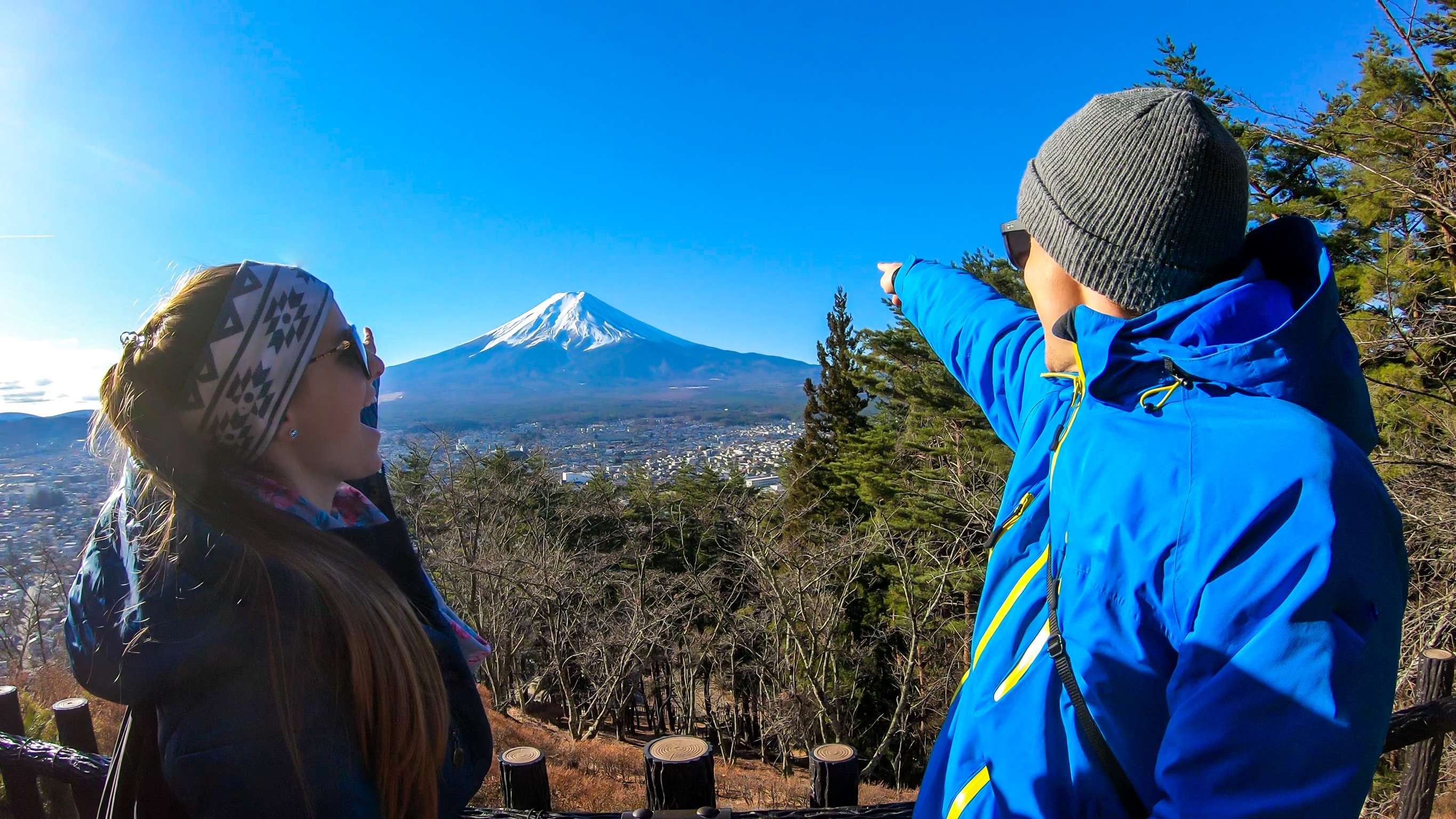 A Couple Standing On The Hilltop Above Chureito Pagoda Japan And Pointing At Mt Fuji In The