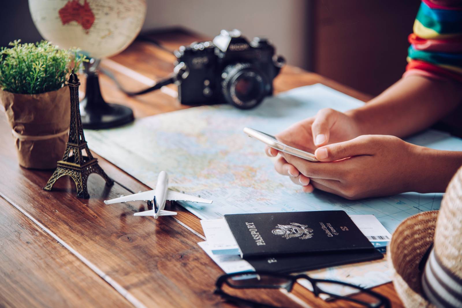 Traveller planning a trip with a map, passport, phone, and travel essentials on a wooden