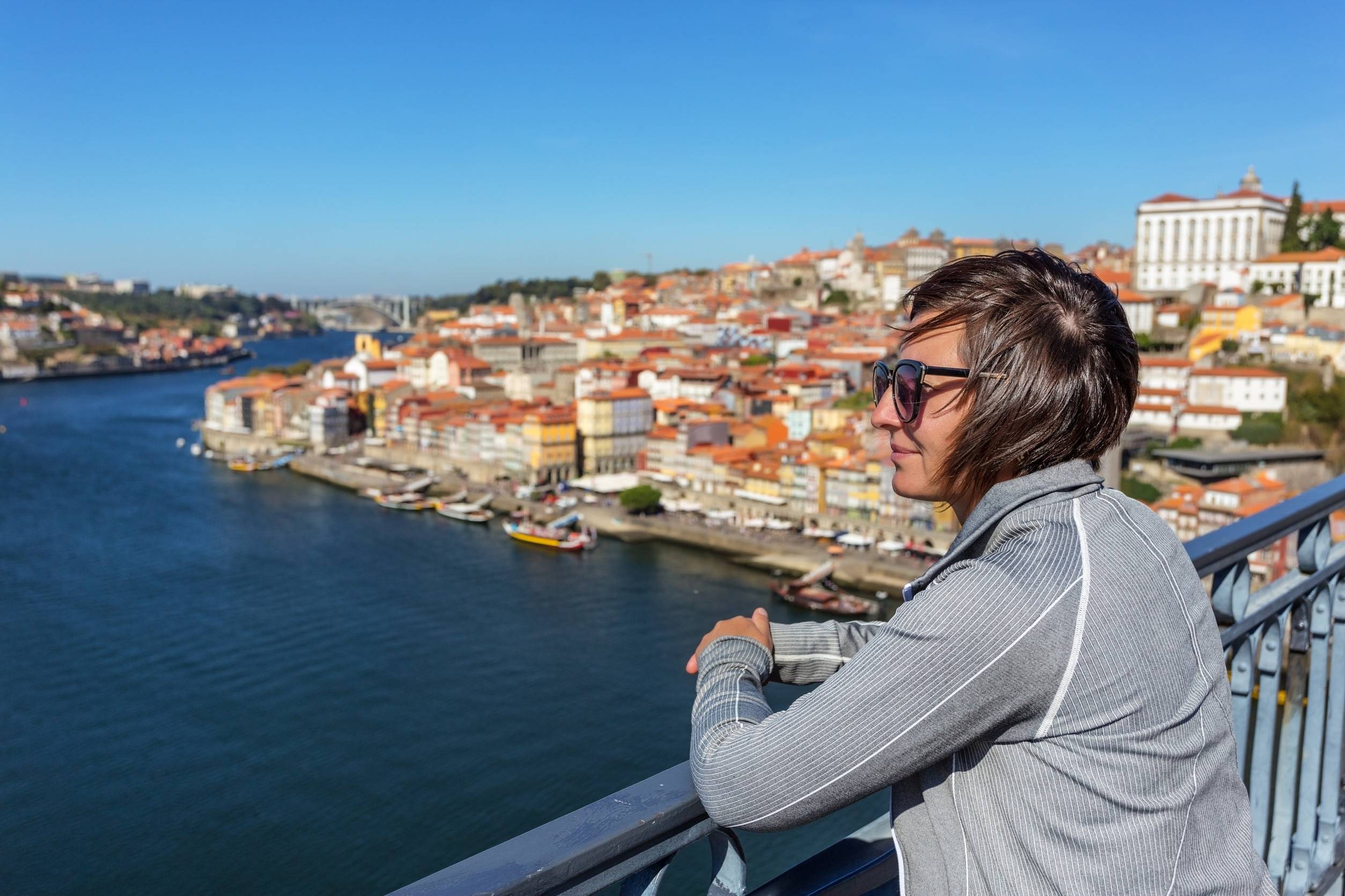 The Girl On The Bridge Of San Luis In The Portuguese City Of Porto Looks At The Landscap